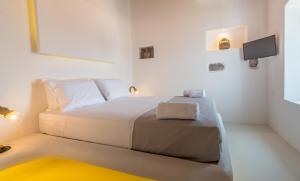 a white bedroom with a bed and a tv at Plaka Suites in Plaka Milou