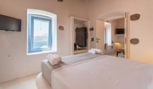 a bedroom with a large white bed with a window at Plaka Suites in Plaka Milou
