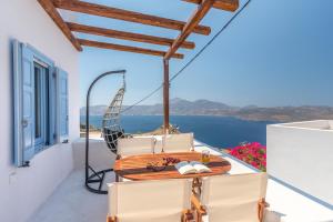 a table and chairs on a balcony with a view of the ocean at Plaka Suites in Plaka Milou