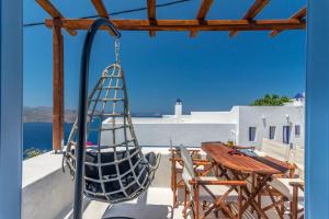 a porch with a swing and a table and chairs at Plaka Suites in Plaka Milou