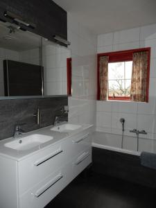 een badkamer met 2 wastafels, een bad en een raam bij B&B 't Hekkert in Gorssel