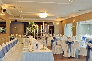 un salón de banquetes con mesas blancas y sillas blancas en Maples House Hotel, en Dublín