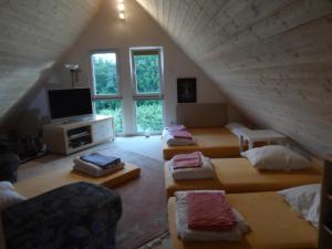a attic room with four beds and a television at Pension am Kirschgarten in Gößweinstein