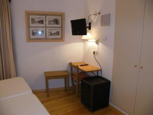 Habitación pequeña con cama y mesa con lámpara. en Hotel de La Font Peralada en Peralada