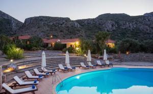 a resort with a swimming pool and chairs and mountains at Monemvasia Village (ex Topalti) in Monemvasia