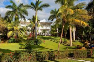 ein Haus mit Palmen und Blumen davor in der Unterkunft Azul Hotel & Retreat in Playa Azul