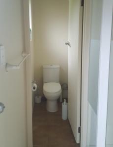 a bathroom with a white toilet in a stall at Hot Water Beach Cottage in Hotwater Beach