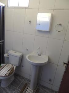 a white bathroom with a toilet and a sink at Pousada Centaurus in Alto Paraíso de Goiás