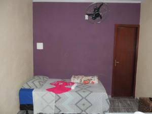a bedroom with a purple wall with a bed and a fan at Pousada Centaurus in Alto Paraíso de Goiás