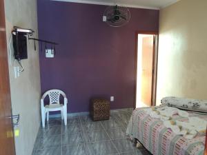 a bedroom with a bed and a white chair at Pousada Centaurus in Alto Paraíso de Goiás