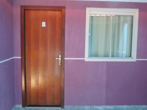 a door in a purple wall with a window at Pousada Centaurus in Alto Paraíso de Goiás