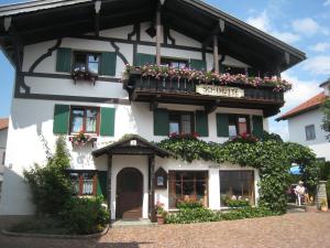 a white building with a balcony with flowers on it at Pension Schihütte in Oberstaufen