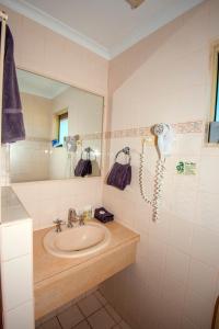 
a bathroom with a sink, mirror, and bathtub at Ningaloo Reef Resort in Coral Bay
