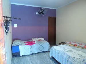 a bedroom with two beds and a purple wall at Pousada Centaurus in Alto Paraíso de Goiás