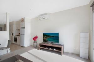 a living room with a tv on a white wall at Astra Apartments Glen Waverley @ViQi in Glen Waverley