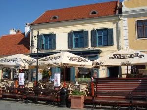 um restaurante com mesas e guarda-sóis em frente a um edifício em Portré Panzió em Kőszeg