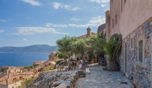 a group of people sitting on a street near the water at Bastione Malvasia Hotel (ex New Malvasia) in Monemvasia