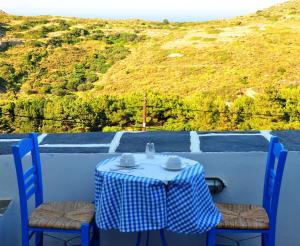 a table with a blue and white checkered table cloth and two chairs at Margarita Hotel in Kythira