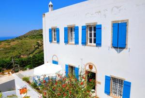 a white building with blue shutters and a hill at Margarita Hotel in Kythira