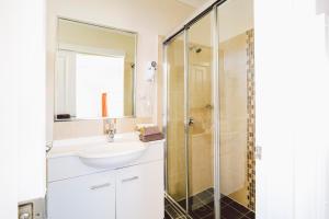 a bathroom with a shower, sink, and mirror at Boulevard Motel in Stanthorpe