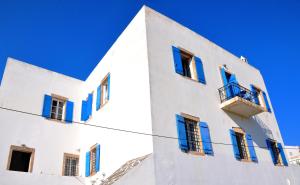 a white building with blue windows and a balcony at Margarita Hotel in Kythira