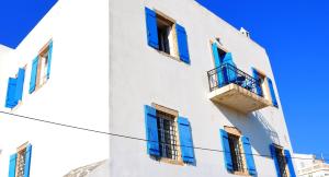 a white building with blue windows and a balcony at Margarita Hotel in Kythira