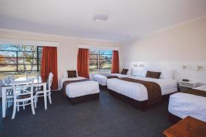 a hotel room with two beds and two tables at Boulevard Motel in Stanthorpe