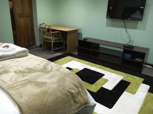 ケンプトンパークにあるTassili Lodgeのベッドと机とテレビのある寝室