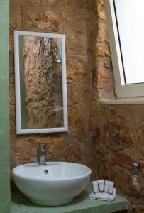 a bathroom with a sink and a mirror on a stone wall at Sol Pedra Villas in Skala Marion