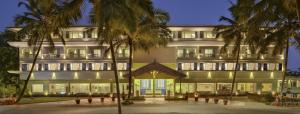 a large building with palm trees in front of it at Sterling Goa Varca in Varca
