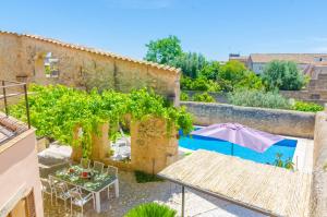 een patio met een tafel, een parasol en een zwembad bij Sa Casa Vella in Vilafranca de Bonany