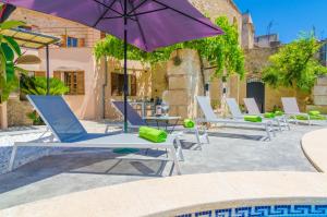 een groep stoelen en een parasol op een patio bij Sa Casa Vella in Vilafranca de Bonany