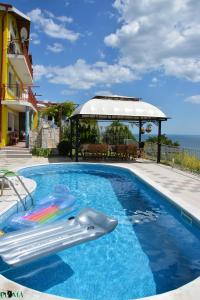 a swimming pool with a gazebo next to the ocean at Villa Puma in Balchik