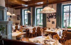 a restaurant with wooden tables and chairs and windows at Landgasthof zum Mühlenteich in Eggersdorf