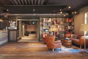 a library with a couch and chairs and books at Bretterbude Heiligenhafen in Heiligenhafen