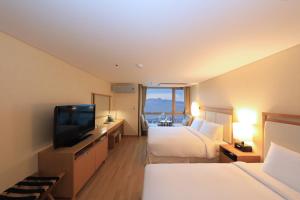 a hotel room with two beds and a flat screen tv at Ocean Suites Jeju Hotel in Jeju