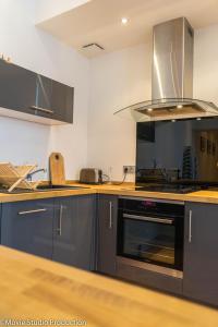 uma cozinha com armários cinzentos e um forno com placa de fogão em Charming Haussmannien 50m2 - city center em Rouen