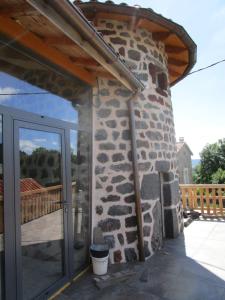 - un bâtiment en pierre avec une porte en verre sur une terrasse dans l'établissement Gite La Tourterelle, à Le Brignon