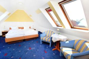 een slaapkamer met een bed en 2 stoelen en een tafel bij Hotel Pension Kirschstein in Wolgast