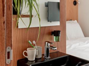 a bathroom with a sink with a coffee maker and cups at Q-Factory Hotel in Amsterdam