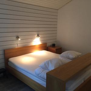 1 dormitorio con cama blanca y cabecero de madera en Stuga i Ullared en Ullared