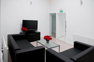 sala de estar con 2 sofás negros y TV en Hostal Central en Fuente-Álamo