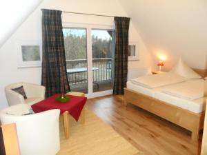 Schlafzimmer mit einem Bett und einem Tisch sowie einem Balkon in der Unterkunft Pension am Kirschgarten in Gößweinstein