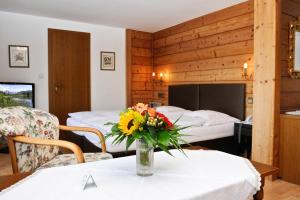 una camera con due letti e un vaso di fiori su un tavolo di Hotel Helga a Seefeld in Tirol
