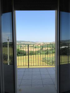 una puerta de cristal abierta con vistas a un campo en Appartamento l'Ulivo, en Gradara