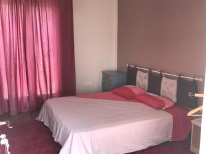 1 dormitorio con 1 cama con sábanas rojas y cortinas rojas en finca las gateras, en Villamartín
