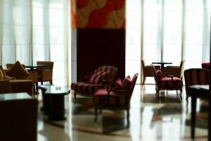 a room with chairs and tables and large windows at Kingsgate Hotel Doha by Millennium Hotels in Doha