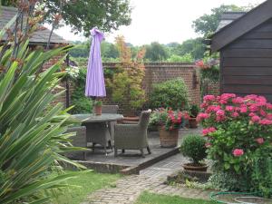 a garden area with a table, chairs, and flowers at The Coach House in Rudgwick
