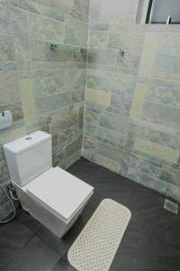 een badkamer met een toilet en een tegelwand bij My Home Guest in Polonnaruwa