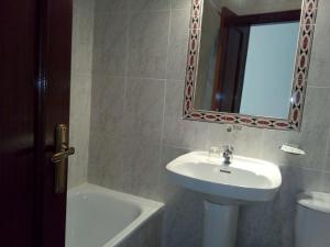 a white sink sitting under a mirror in a bathroom at Hostal Ávila in Ocaña